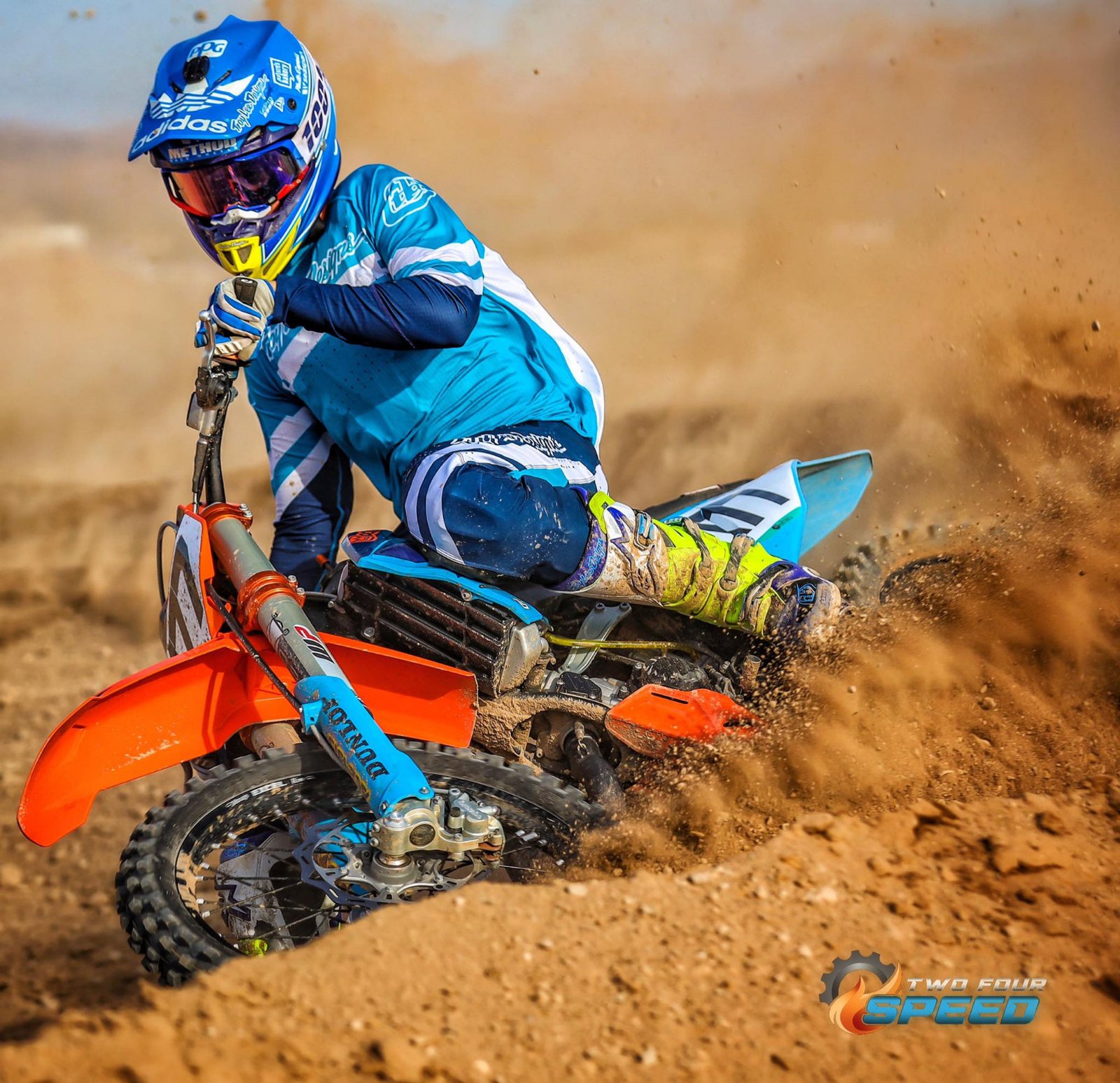 A motocross rider cornering hard through deep berm dirt