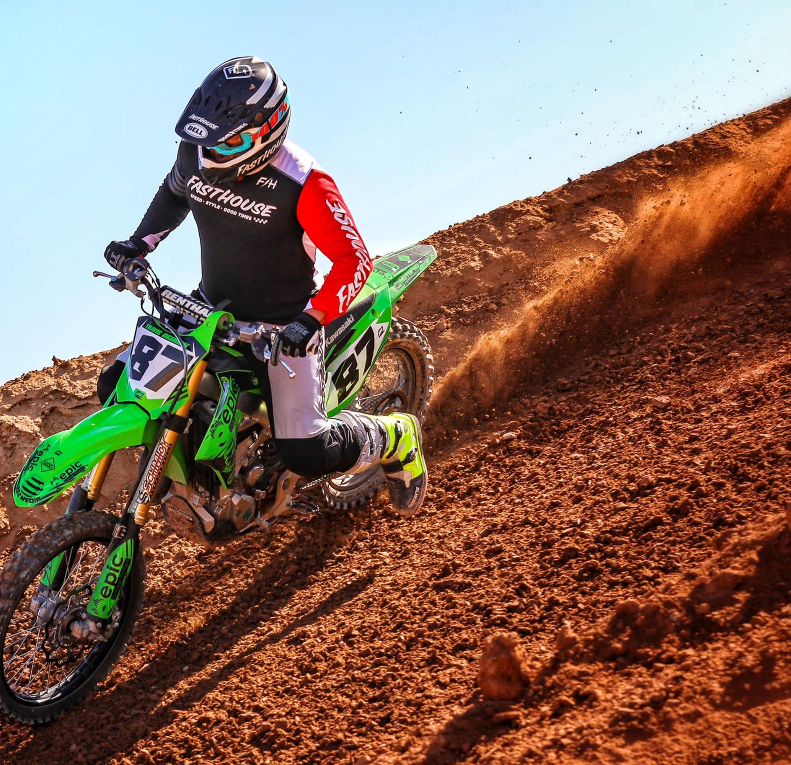 A rider climbing a steep red-dirt hill