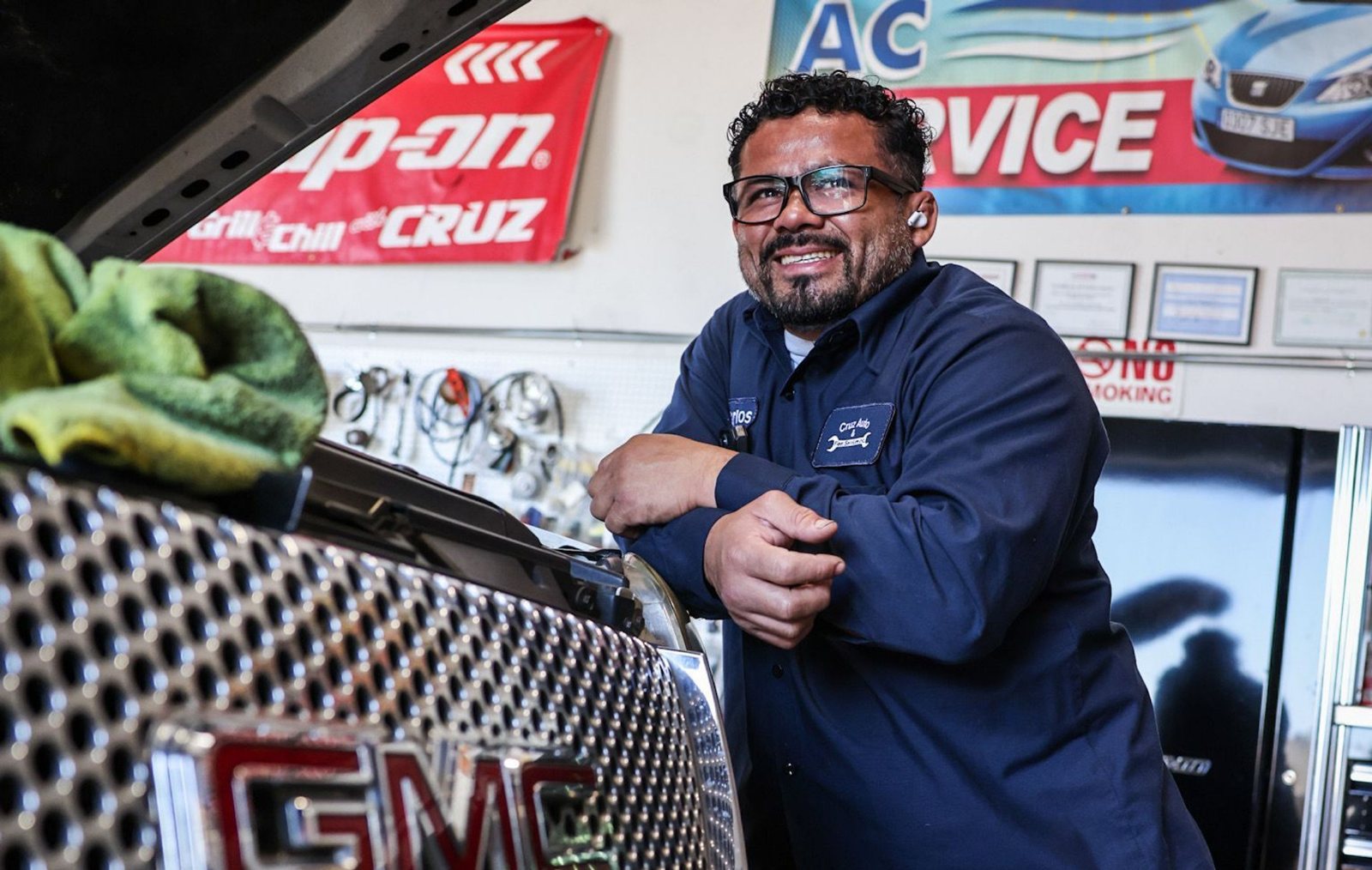 A technician leaning on a truck bonnet at an AC service bay
