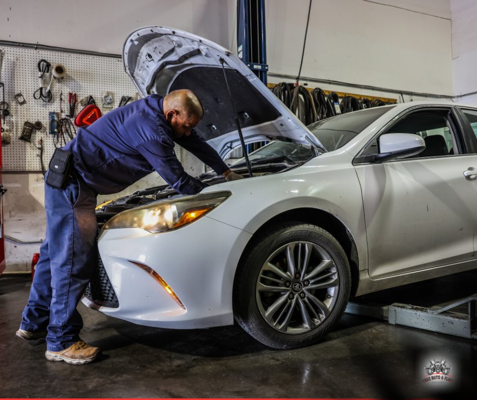 A technician working under the bonnet of a saloon