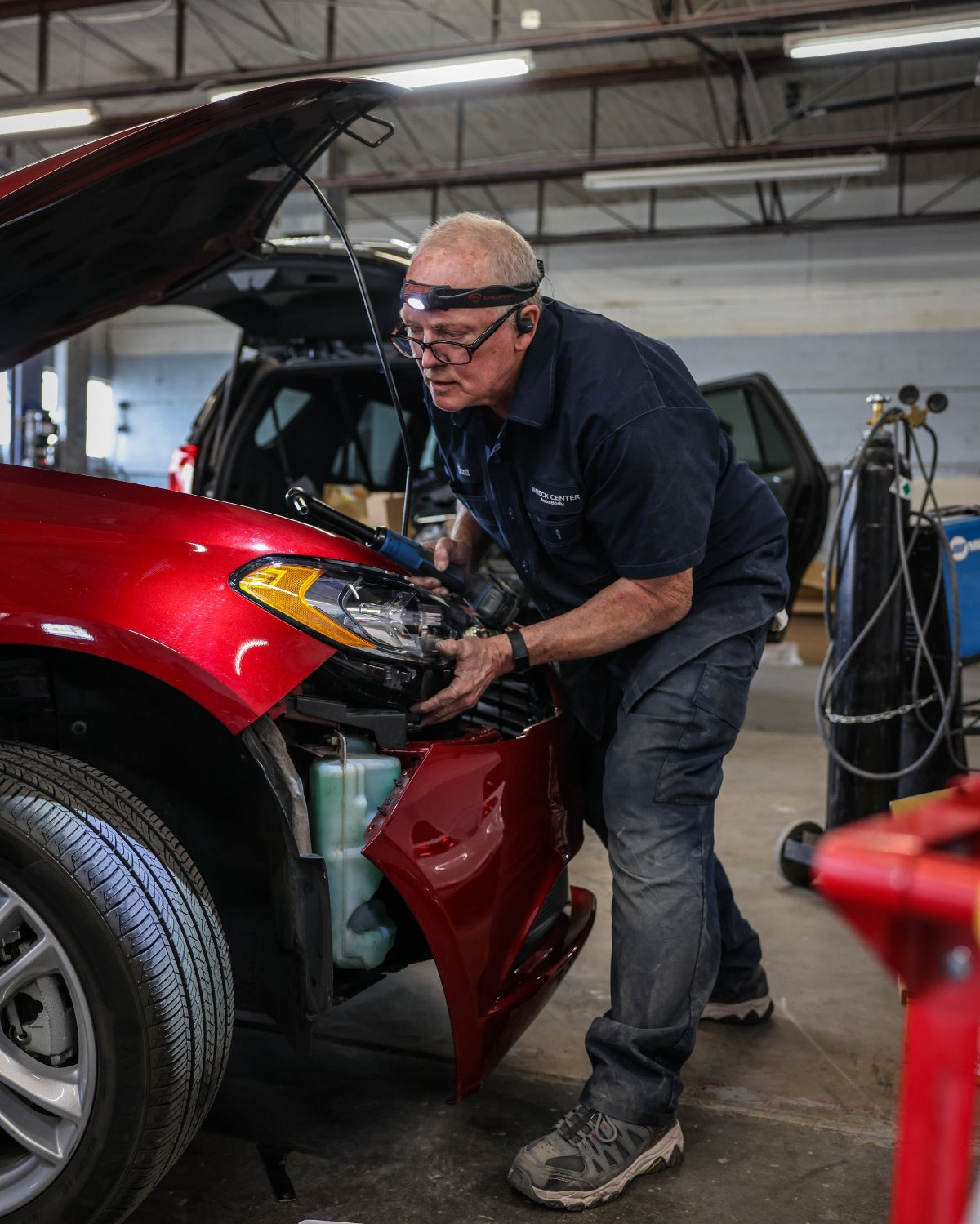 A technician working on the front of a red SUV